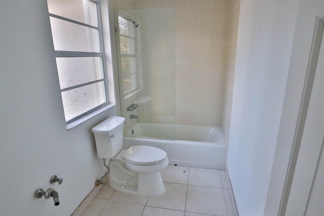 bathroom with toilet, tile patterned flooring, and tiled shower / bath combo