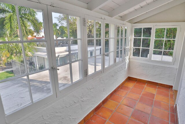 unfurnished sunroom featuring lofted ceiling with beams