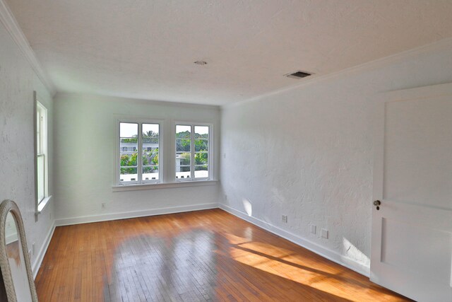 spare room with hardwood / wood-style floors and crown molding