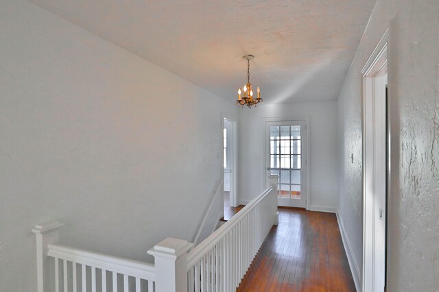 corridor with a chandelier and dark hardwood / wood-style floors