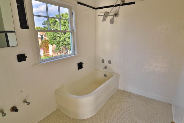 bathroom with tile walls, tile patterned flooring, and tiled shower / bath