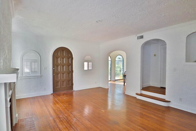 foyer entrance with crown molding, wood-type flooring, and a textured ceiling