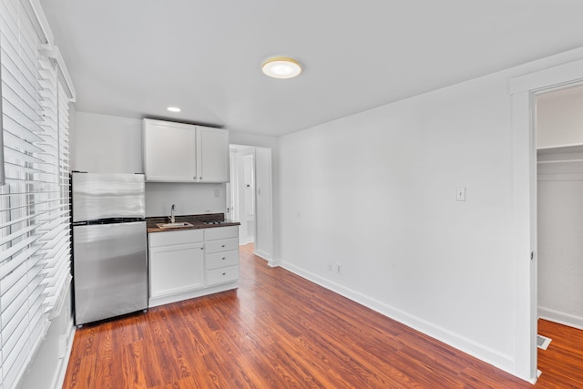 kitchen with white cabinetry, dark wood-type flooring, sink, and stainless steel fridge