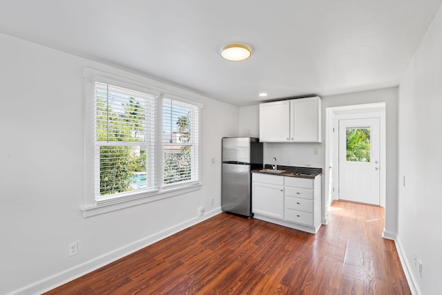 kitchen with sink, dark wood-type flooring, stainless steel refrigerator, and white cabinets