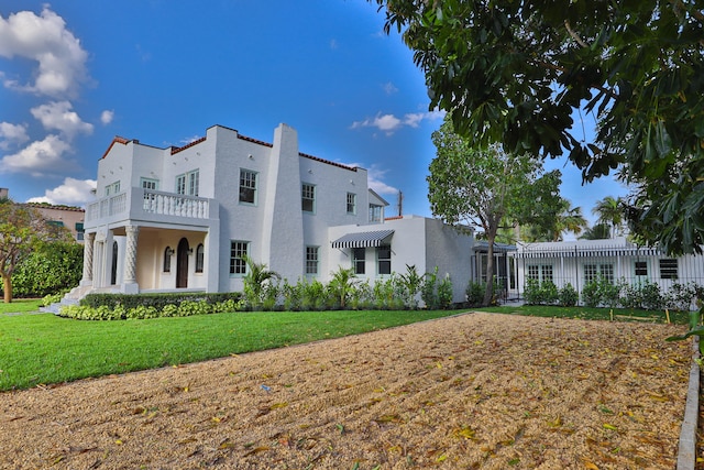 view of front of property featuring a balcony and a front lawn