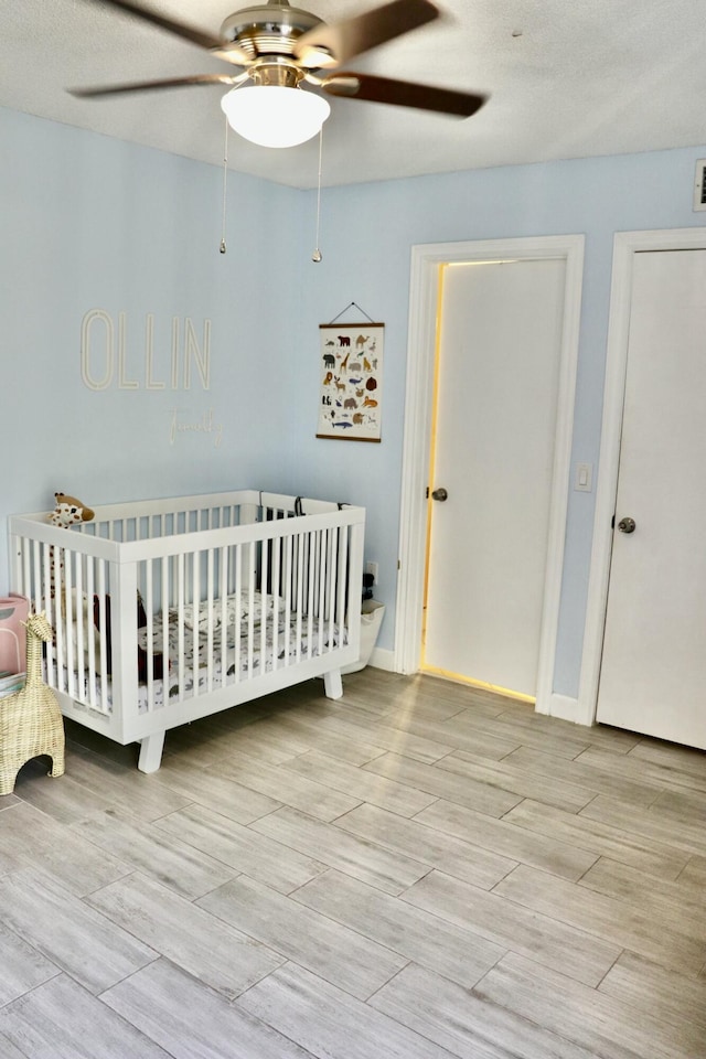 bedroom with a crib and ceiling fan