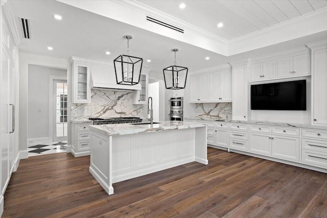 kitchen with white cabinets, dark hardwood / wood-style flooring, and an island with sink