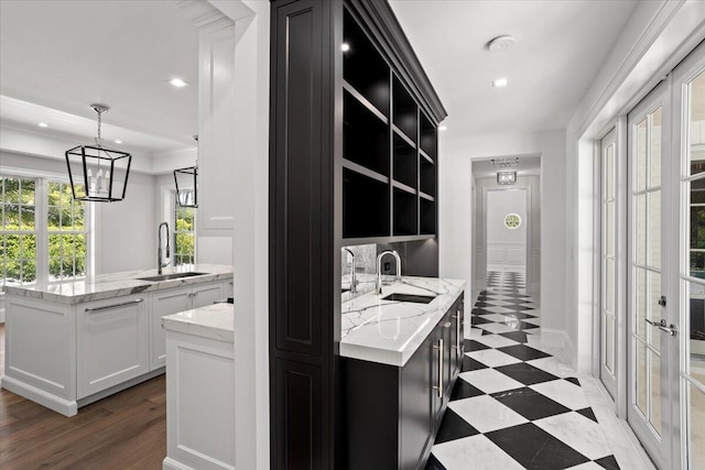 kitchen with a notable chandelier, white cabinetry, sink, and hanging light fixtures