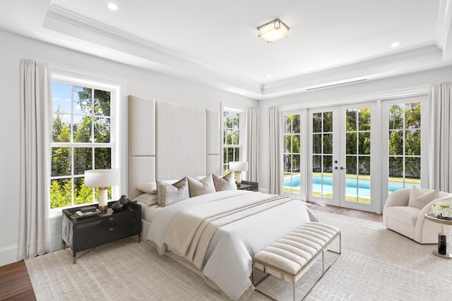 bedroom with french doors, crown molding, access to exterior, a tray ceiling, and light hardwood / wood-style floors