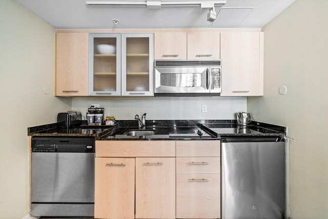 kitchen with appliances with stainless steel finishes, sink, dark stone counters, and light brown cabinets