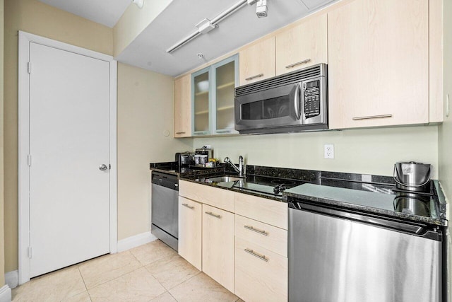 kitchen featuring light tile patterned floors, appliances with stainless steel finishes, dark stone counters, and light brown cabinets