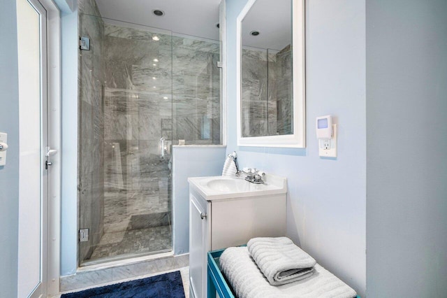 bathroom featuring a shower with door and vanity