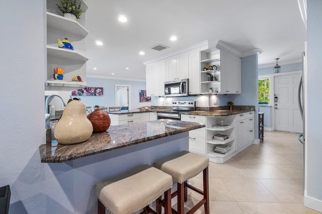 kitchen with ornamental molding, kitchen peninsula, white cabinets, and appliances with stainless steel finishes