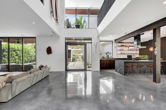 entrance foyer with sink, concrete flooring, and a high ceiling