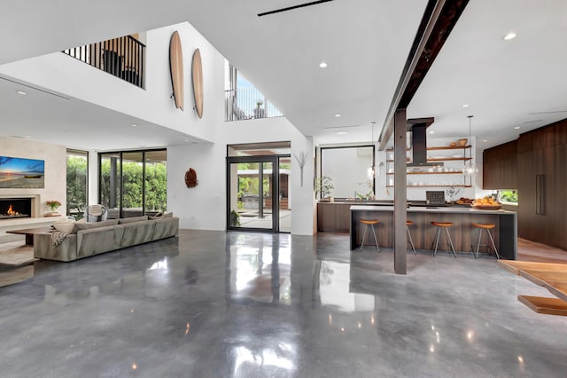 kitchen featuring exhaust hood, a kitchen island, a kitchen bar, and concrete flooring