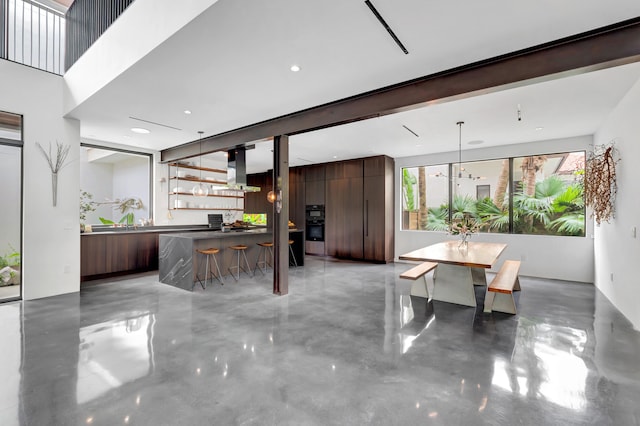 kitchen with range hood, hanging light fixtures, concrete floors, and black double oven