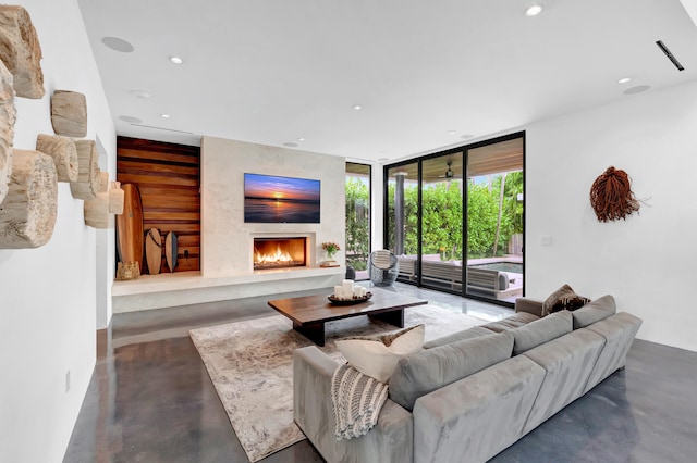 living room featuring wooden walls, a wall of windows, and a large fireplace