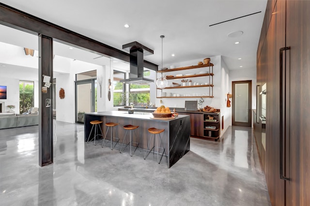 kitchen with wall chimney exhaust hood, a kitchen island, a kitchen bar, and a healthy amount of sunlight