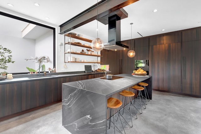 bar with wooden walls, sink, dark brown cabinets, island range hood, and decorative light fixtures