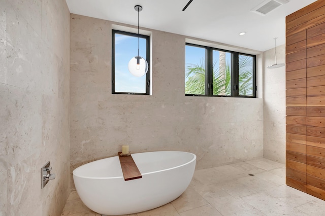 bathroom featuring plenty of natural light, tile floors, and a washtub