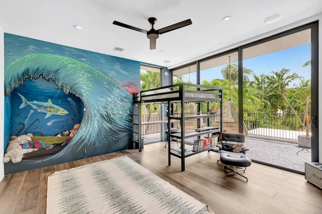 bedroom with a wall of windows, ceiling fan, and light hardwood / wood-style flooring