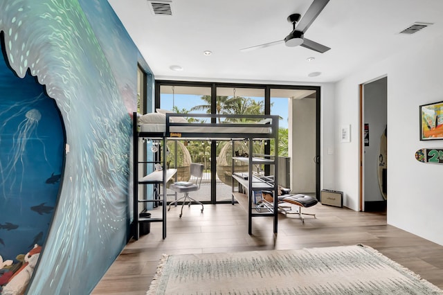 interior space with expansive windows, ceiling fan, and light wood-type flooring