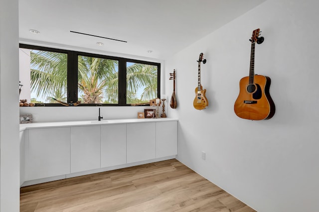 kitchen with light hardwood / wood-style floors, white cabinetry, and sink