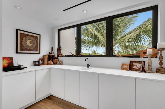 kitchen with light hardwood / wood-style floors, white cabinets, and sink