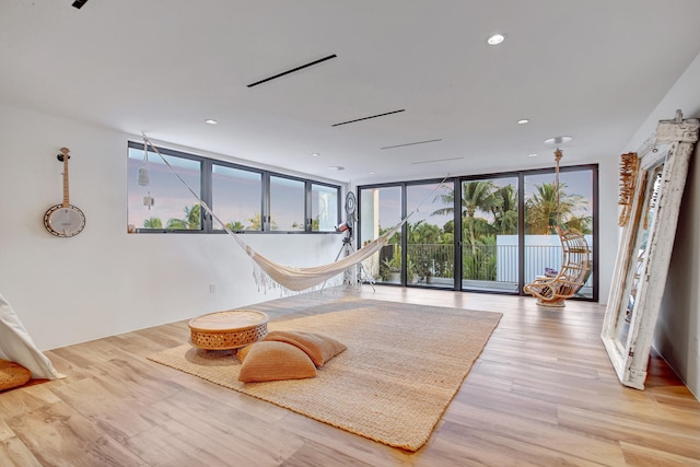 living area with a wall of windows and light wood-type flooring