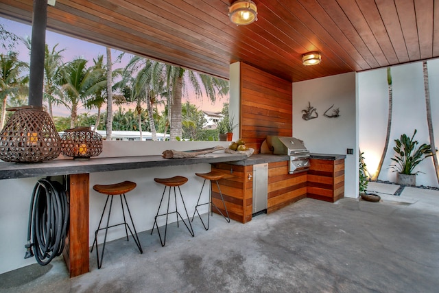 patio terrace at dusk with exterior bar, exterior kitchen, and area for grilling