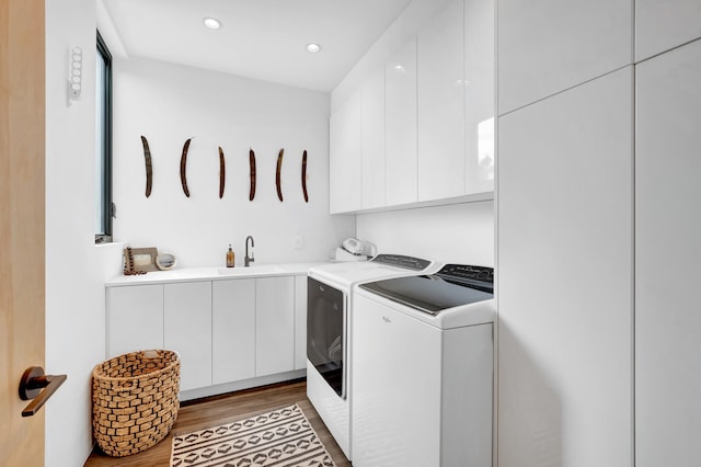 laundry room with light hardwood / wood-style floors, cabinets, washer and dryer, and sink