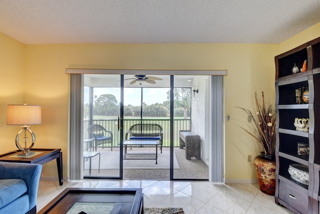 doorway to outside featuring ceiling fan, light tile patterned floors, and a textured ceiling