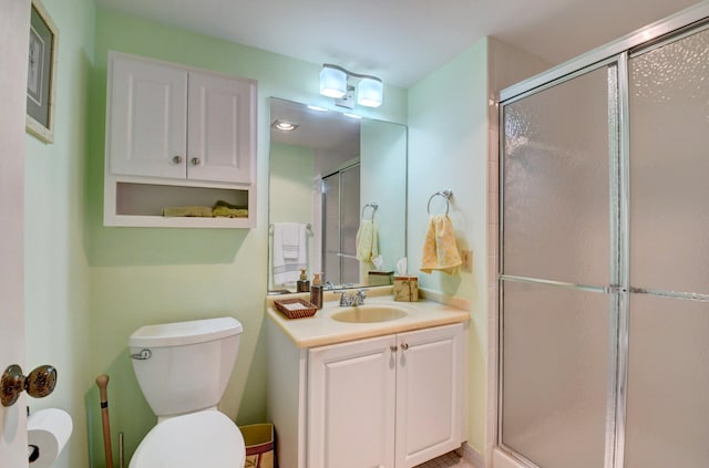 bathroom with a shower with door, vanity, and toilet