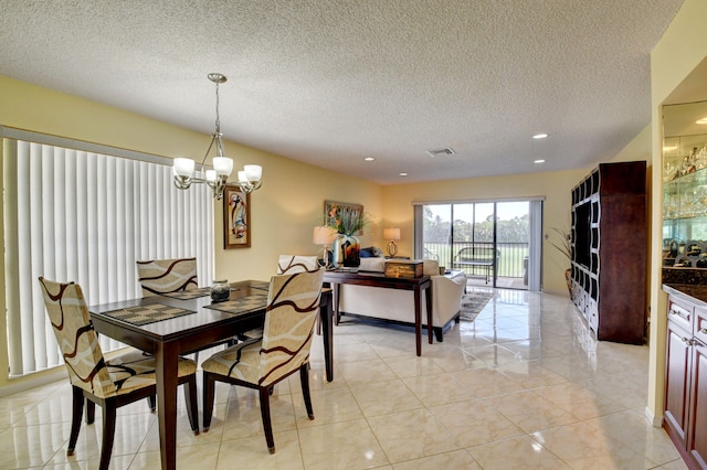 tiled dining area featuring a textured ceiling and an inviting chandelier