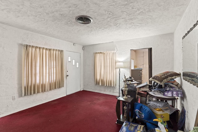 misc room featuring a textured ceiling and dark carpet