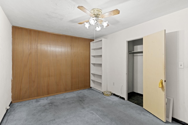 unfurnished bedroom with a closet, dark carpet, and ceiling fan