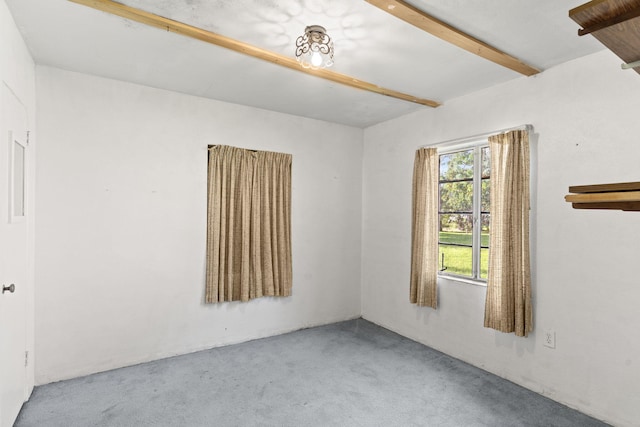 empty room featuring light colored carpet and beamed ceiling