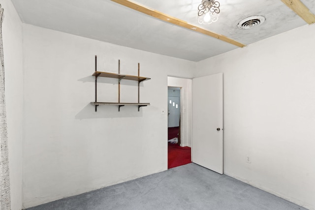 spare room featuring light colored carpet and beam ceiling