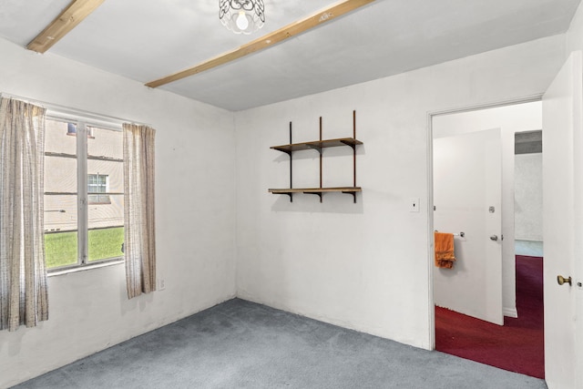 carpeted empty room featuring beam ceiling