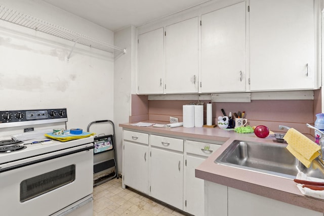 kitchen with sink, light tile floors, range, and white cabinetry