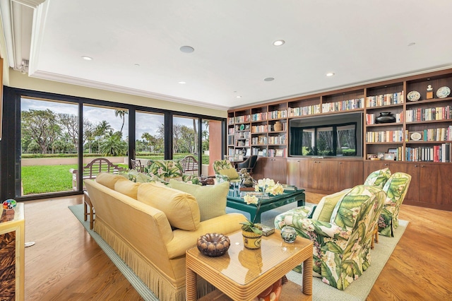 living room with built in features, ornamental molding, and light hardwood / wood-style flooring