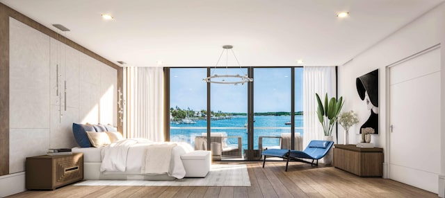 bedroom featuring an inviting chandelier, a wall of windows, a water view, and light wood-type flooring