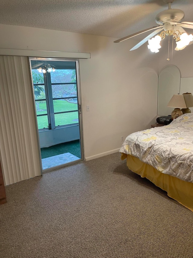 unfurnished bedroom with a textured ceiling, dark colored carpet, and ceiling fan