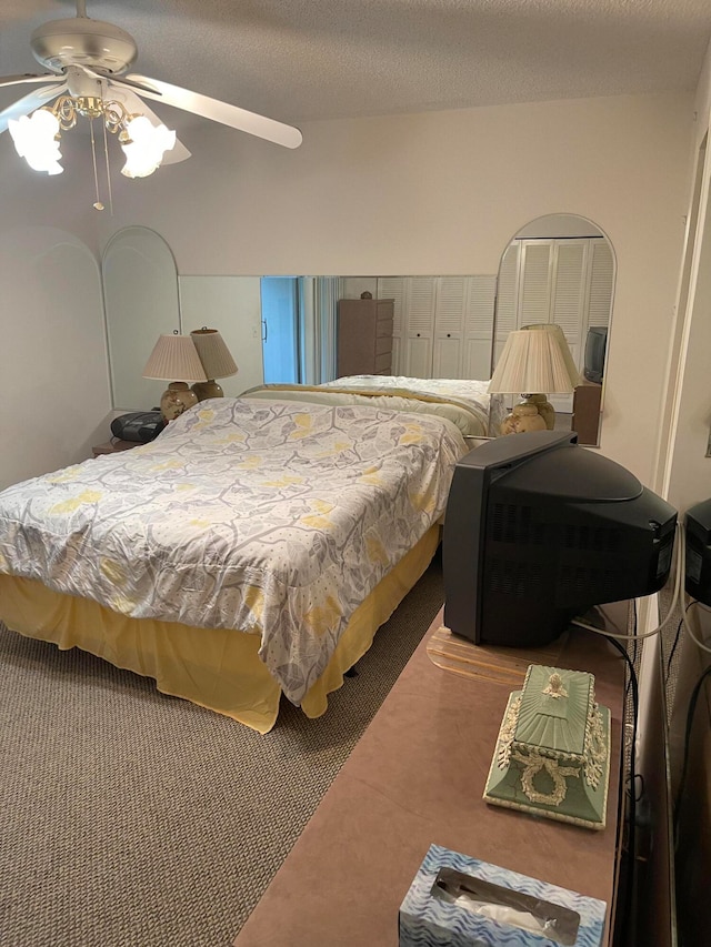 carpeted bedroom with ceiling fan and a textured ceiling