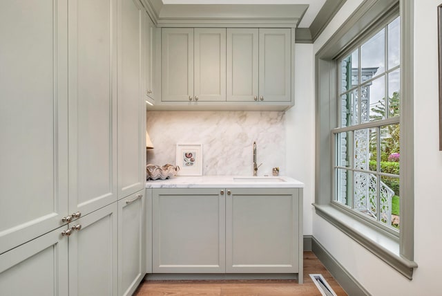 interior space with gray cabinets, sink, light hardwood / wood-style flooring, and tasteful backsplash