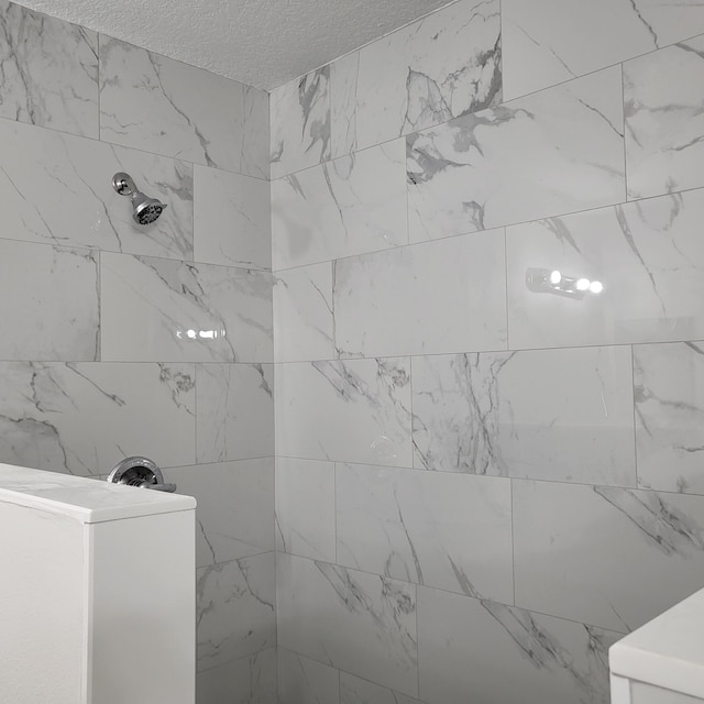 bathroom featuring a tile shower and washer / dryer