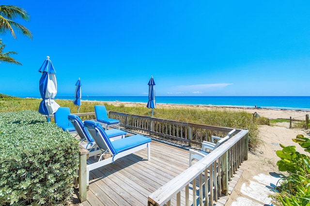 wooden terrace featuring a water view and a view of the beach