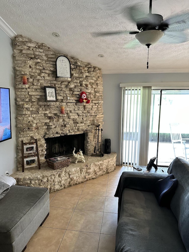 tiled living room featuring ceiling fan, ornamental molding, vaulted ceiling, a textured ceiling, and a stone fireplace