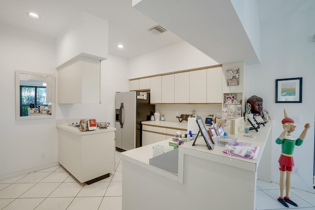 kitchen with stainless steel fridge with ice dispenser, kitchen peninsula, light tile flooring, and white cabinets