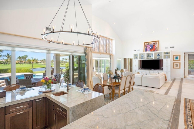 interior space featuring high vaulted ceiling, dark brown cabinets, a chandelier, and light stone counters